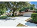 Brick home with mature trees, long driveway, two-car garage, and attractive landscaping at 316 Dornoch Ct, Winter Springs, FL 32708