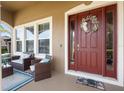 Inviting front porch features cozy seating, a wreath on the red door, and ample natural light at 3551 Statham Dr, Apopka, FL 32712