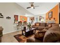 Spacious living room with tile floors, opening to kitchen bar with comfortable brown leather sofa set at 5545 Devonbriar Way # 206, Orlando, FL 32822