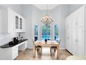 Bright dining area features a wooden table, a chandelier, views of the pool, and white cabinets for storage at 718 Glen Eagle Dr, Winter Springs, FL 32708