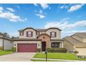 Charming two-story home with a well-manicured lawn, stone accents, and a two-car garage with crimson doors and shutters at 731 Arbor Pointe Ave, Minneola, FL 34715