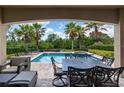 Covered patio space with comfortable seating and outdoor dining, overlooking the pool and beautiful landscaping at 796 Desert Mountain Ct, Reunion, FL 34747