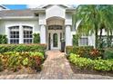 Inviting front entrance with brick walkway, beautiful landscaping, and white columns at 1932 Reed Hill Dr, Windermere, FL 34786