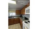 Functional kitchen featuring wooden cabinets, a stainless steel sink, and white appliances at 226 Canna Dr, Davenport, FL 33897