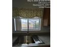 Close-up of a kitchen sink with a window view of the backyard and a decorative valance above at 226 Canna Dr, Davenport, FL 33897