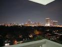 Balcony view of city skyline at night with lush trees and rooftops below at 400 E Colonial Dr # 910, Orlando, FL 32803