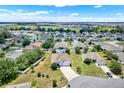 Expansive aerial view of a residential neighborhood showcases various homes, lush greenery, and a serene lake at 804 Glen Creek Ct, Fruitland Park, FL 34731