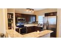 Modern kitchen with stainless steel appliances, dark wood cabinets, and granite countertops at 8767 Grandee Dr, Orlando, FL 32829