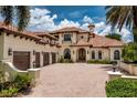 Beautiful Mediterranean-style home featuring a three-car garage and a brick paved driveway at 9253 Tibet Pointe Cir, Windermere, FL 34786