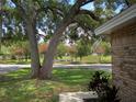 Inviting brick home featuring a well-manicured lawn, large shade tree, and colorful landscaping at 2181 Wekiwa Oaks Dr, Apopka, FL 32703