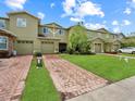 Attractive two-story home featuring a lush green lawn and brick driveway at 2311 Chatham Place Dr, Orlando, FL 32824