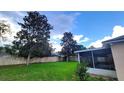 Green backyard featuring a screened-in lanai and a privacy fence at 2555 Palmetto Ridge Cir, Apopka, FL 32712