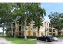Beige three-story condo building with mature trees, manicured shrubs, and assigned parking at 2598 Robert Trent Jones Dr # 1030, Orlando, FL 32835