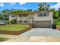 Split-level home with 1 car garage, light-colored paint, and neatly kept landscaping and lawn at 6416 Jackwood Ct, Orlando, FL 32818