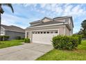 Beige two-story home featuring a large two-car garage and manicured shrubbery at 8113 Sun Palm Dr, Kissimmee, FL 34747