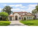 Elegant stucco home featuring a tile roof, arched entryway, and lush landscaping at 11018 Lake Butler Blvd, Windermere, FL 34786