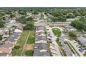 An aerial view shows homes with many trees, a road, and many parked cars, under a clear sky at 1113 Woodman Way, Orlando, FL 32818