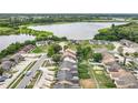 An aerial view of homes in a community near a lake with lush green trees, and clear blue skies at 1113 Woodman Way, Orlando, FL 32818