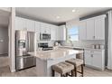 Bright kitchen featuring white cabinets, stainless steel appliances, and a marble-topped island with seating at 1811 Spring Shower Cir, Kissimmee, FL 34744