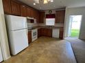 Functional kitchen featuring wood cabinets, white appliances, and a view to the backyard at 2018 Cypress Bay Blvd, Kissimmee, FL 34743