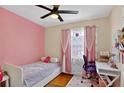 Cozy bedroom with a single bed, pink walls, hardwood floors, and a cute desk at 2021 University Dr, Orlando, FL 32804