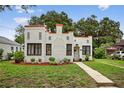 Charming two-story home with orange accents, textured stucco, dark window trim, and a well-manicured front yard at 2021 University Dr, Orlando, FL 32804