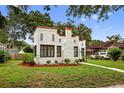 An angle view of a cute home that boasts a stucco exterior, red trim, and green landscaping at 2021 University Dr, Orlando, FL 32804