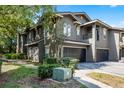 Angle shot of a two-story townhouse with a two-car garage and landscaped yard at 209 Villa Di Este Ter # 205, Lake Mary, FL 32746