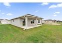 Spacious backyard featuring a covered patio, lush green grass, and a view of neighboring houses at 2644 Hancock Crossing Dr, Bartow, FL 33830