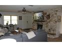 Cozy living room with a stone fireplace, ceiling fan, and comfortable seating, perfect for relaxing at 26586 Se Highway 42, Umatilla, FL 32784