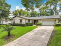 Lovely single-story home with a long driveway and an attached two-car garage, surrounded by lush greenery at 404 Broadview Ave, Altamonte Springs, FL 32701