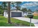 View of the house with gray garage door, mature landscaping and mailbox at 550 Eagle Dr, Daytona Beach, FL 32117