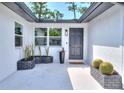 Inviting front porch featuring modern planters, stylish lighting and a dark-colored front door at 550 Eagle Dr, Daytona Beach, FL 32117
