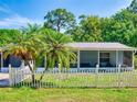 Quaint one-story home with screened porch, framed by palm trees and a white picket fence at 720 Meadow St, Sanford, FL 32773
