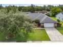 An aerial view of a well-maintained property with a large yard, mature trees, and a driveway leading to a two-car garage at 985 Willow Run Ln, Winter Springs, FL 32708