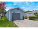 View of the house siding with a gray garage door, small, manicured trees, and landscaped ground covering at 104 Yorktown Pl, Sanford, FL 32771