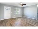 Well-lit living room showcasing wood-look flooring, a new white front door and ample natural light from a window at 1276 Comerwood Dr, Deltona, FL 32738