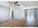 Spacious living room featuring modern wood-look flooring, ceiling fan, and access to the backyard through sliding glass doors at 1276 Comerwood Dr, Deltona, FL 32738