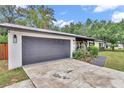 Attached garage with gray door and concrete driveway, complemented by lush landscaping around the home's exterior at 2105 Ne 50Th Pl, Ocala, FL 34479