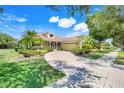 Charming home featuring a lush front yard with palm trees and a brick paver driveway at 217 Lake Cassidy Dr, Kissimmee, FL 34759