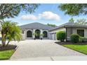 View of a one story home with a well maintained paver driveway, arched windows, and landscaping at 2308 Bur Oak Ct, Oviedo, FL 32766