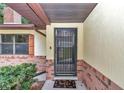 Close-up of front door with security screen and 'Hello' welcome mat on a brick porch at 6421 Nw 61St St, Ocala, FL 34482