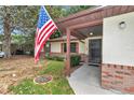 Inviting covered front porch with brick accents, decorative shutters, and an American flag at 6421 Nw 61St St, Ocala, FL 34482