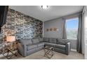 Cozy living room with unique wallpaper, a comfortable gray sectional sofa, and stylish decor at 7524 Marker Ave, Kissimmee, FL 34747