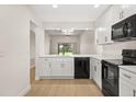 Modern kitchen with white cabinets, black appliances, stone countertop, and hardwood flooring at 7528 Chapelhill Dr, Orlando, FL 32819