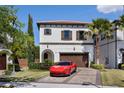 Elegant two-story home with a red tile roof, beautiful landscaping, brick driveway, and a red Ferrari in front at 8113 Via Vittoria Way, Orlando, FL 32819