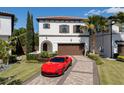 Elegant two-story home with a red tile roof, beautiful landscaping, brick driveway, and a red Ferrari in front at 8113 Via Vittoria Way, Orlando, FL 32819