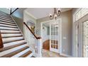 Inviting foyer with staircase, tile flooring, chandelier, and access to rooms with French doors at 10809 Arrowtree Blvd, Clermont, FL 34715
