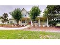 Charming home with a large porch, trees, a red front door, and green shutters on a well-manicured lawn at 10809 Arrowtree Blvd, Clermont, FL 34715