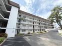 Low angle view of a condo building featuring private balconies, fresh exterior paint and mature trees at 118 S Halifax Ave # 409, Daytona Beach, FL 32118